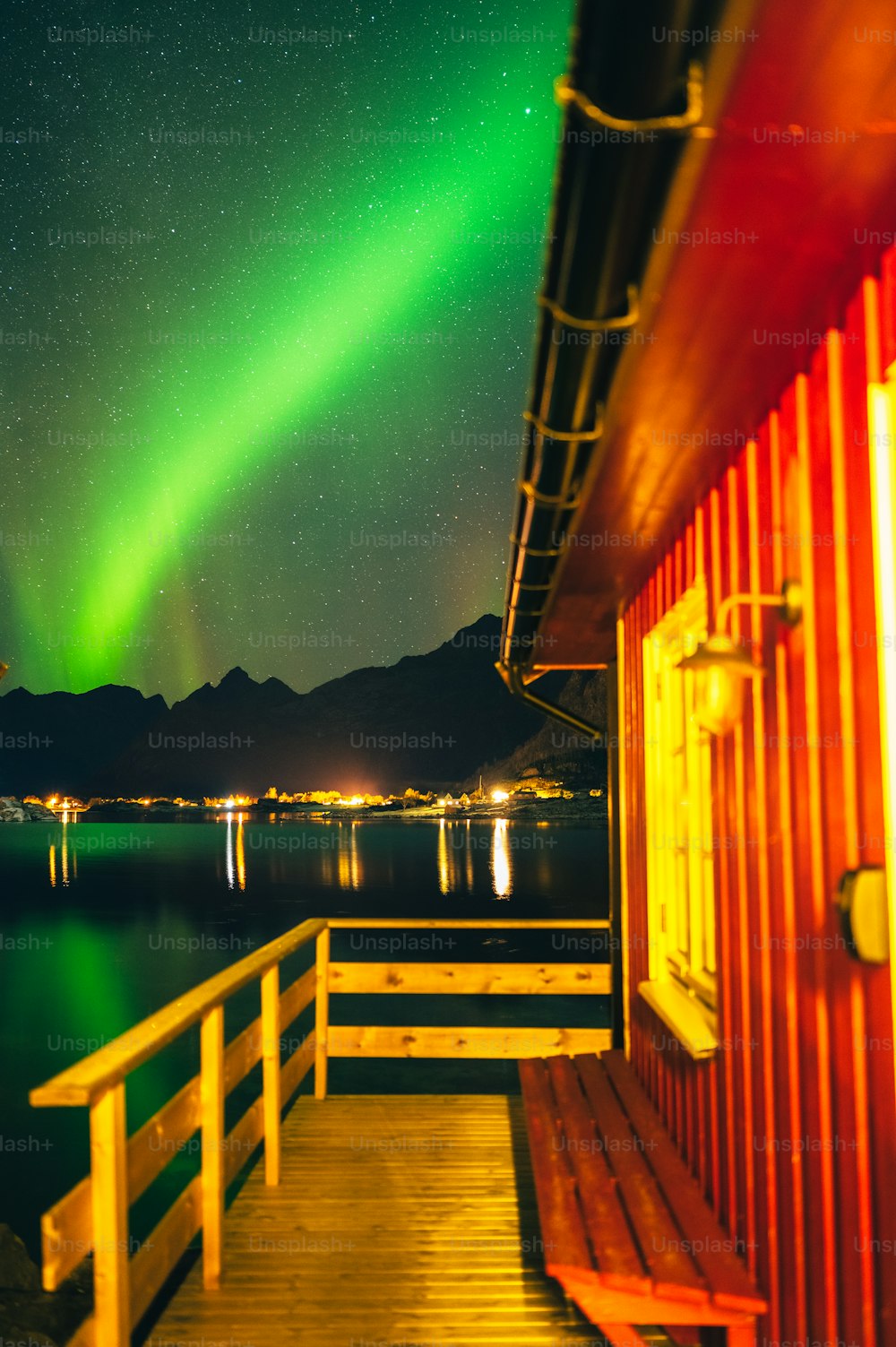 a wooden dock with a green and red aurora light in the background