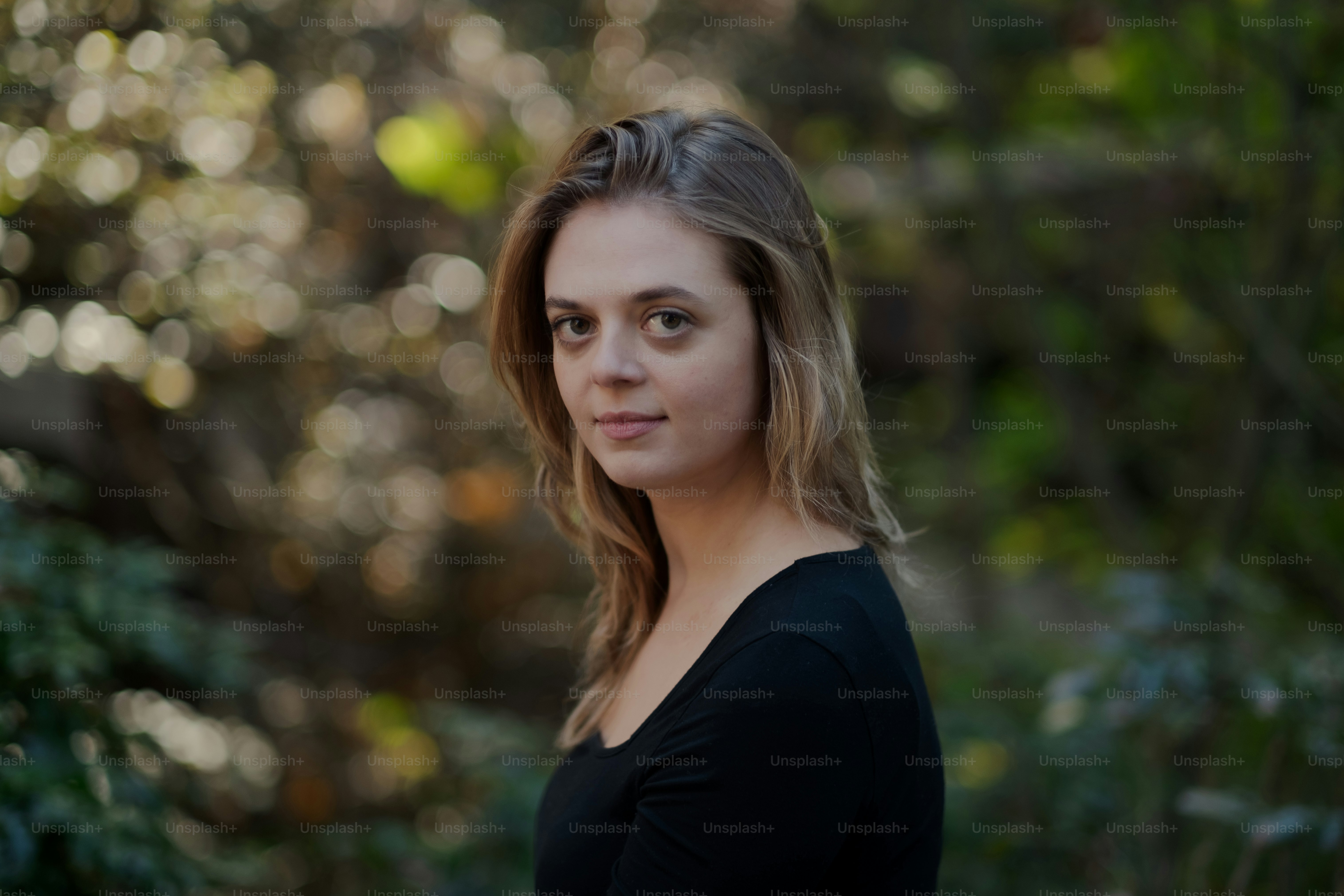 A woman sitting in a park with trees in the background photo – Woman ...
