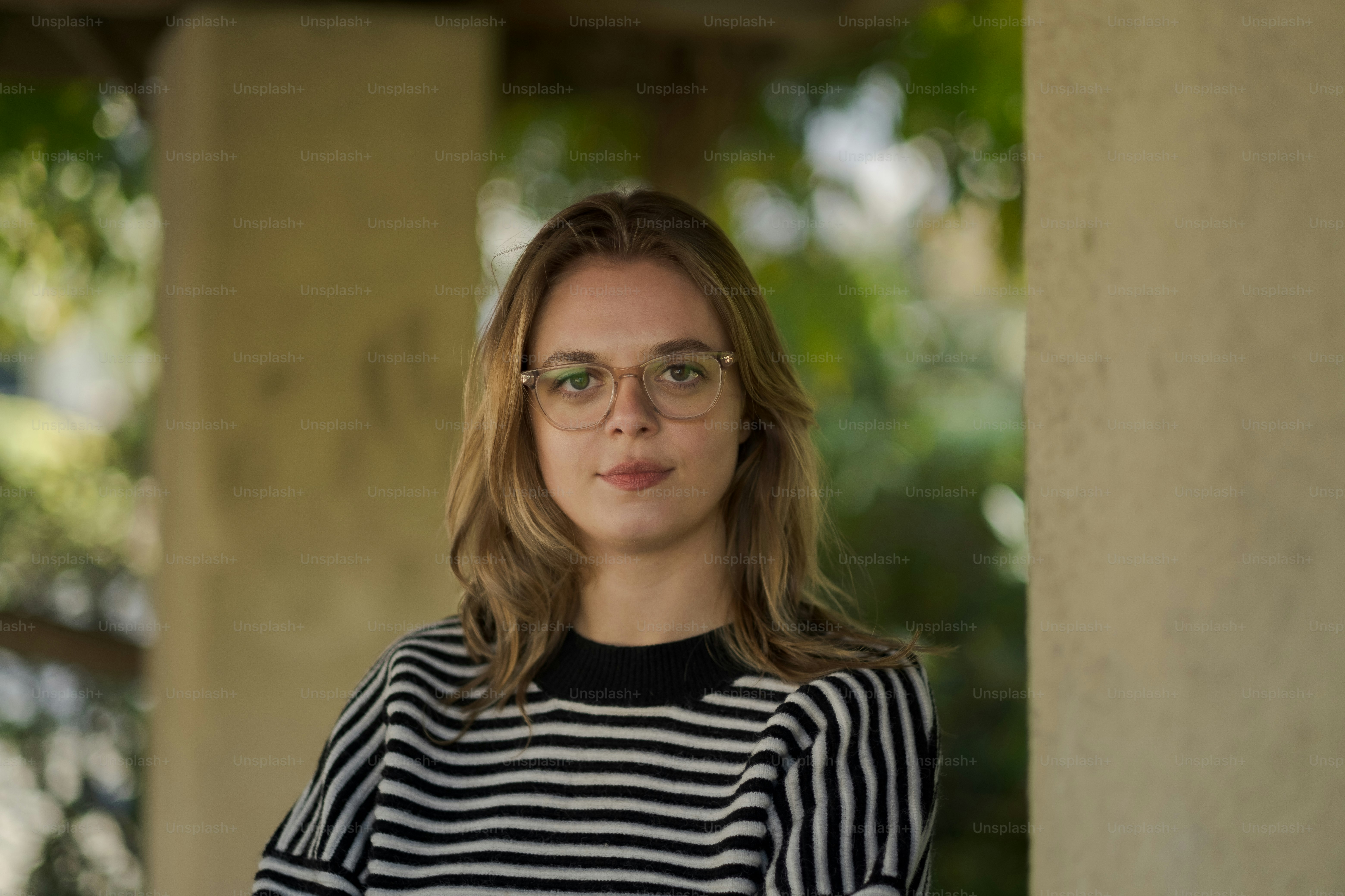 a woman wearing glasses standing next to a pillar