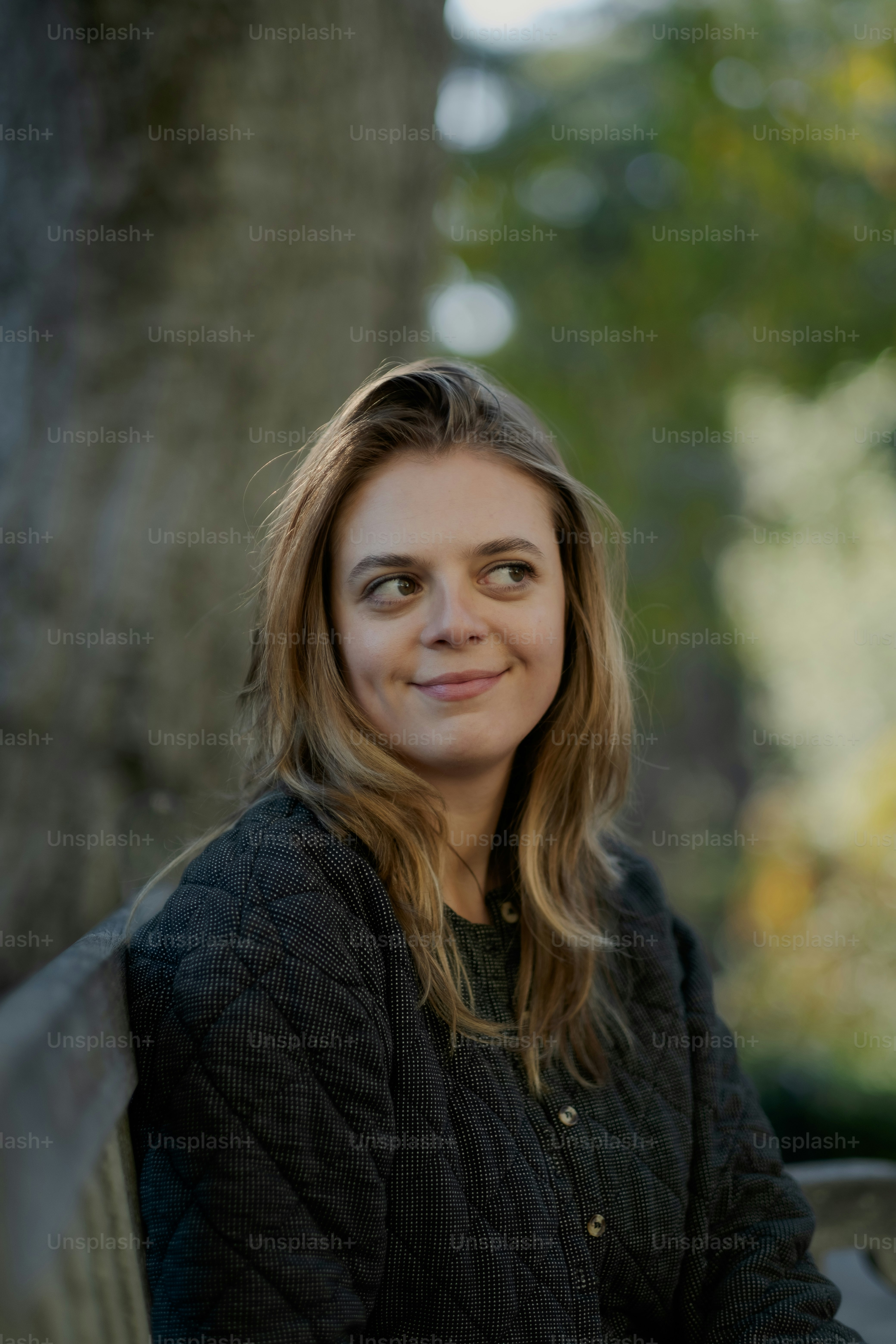 a woman sitting on a bench in front of a tree