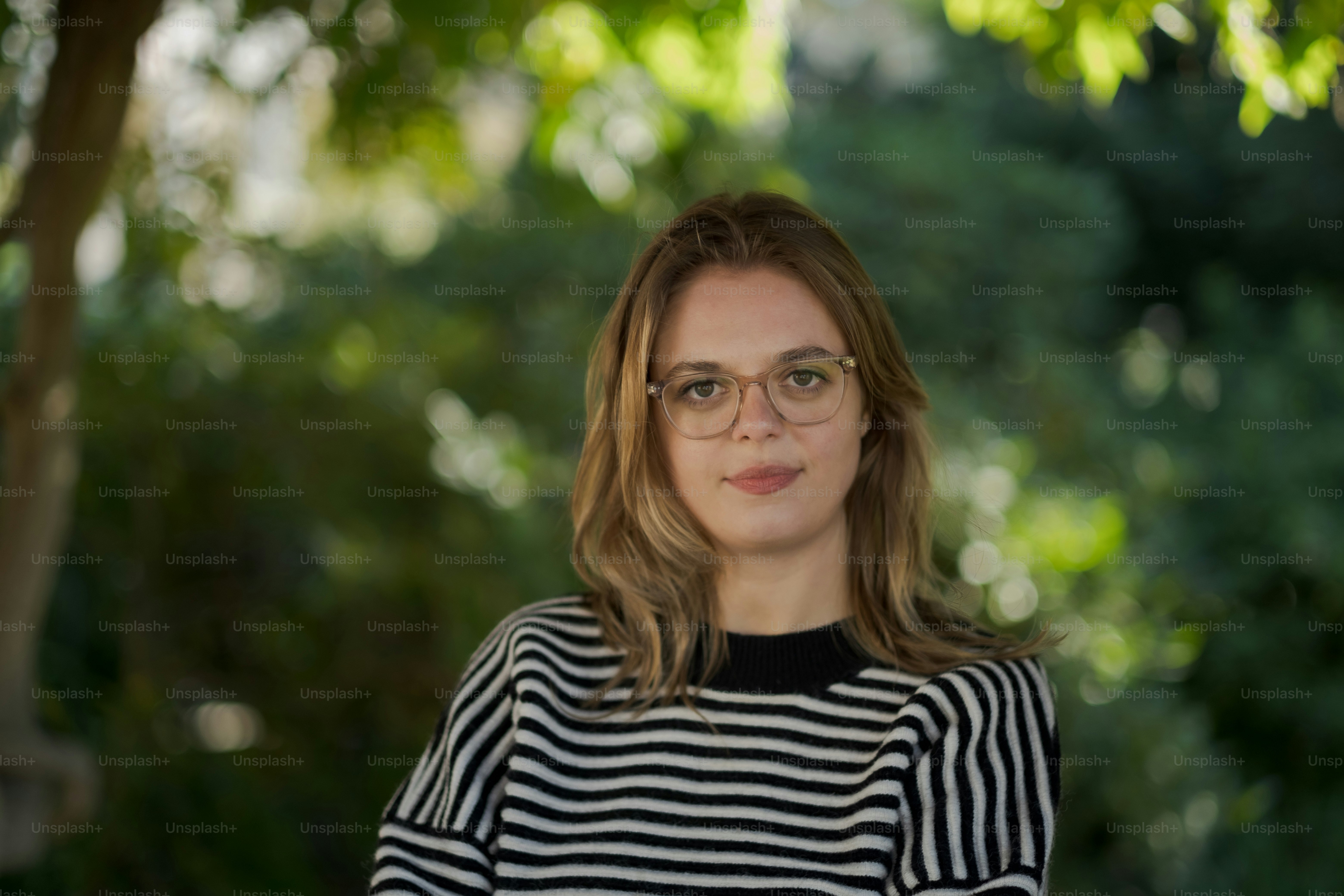 A woman sitting in a park with trees in the background photo – Woman ...
