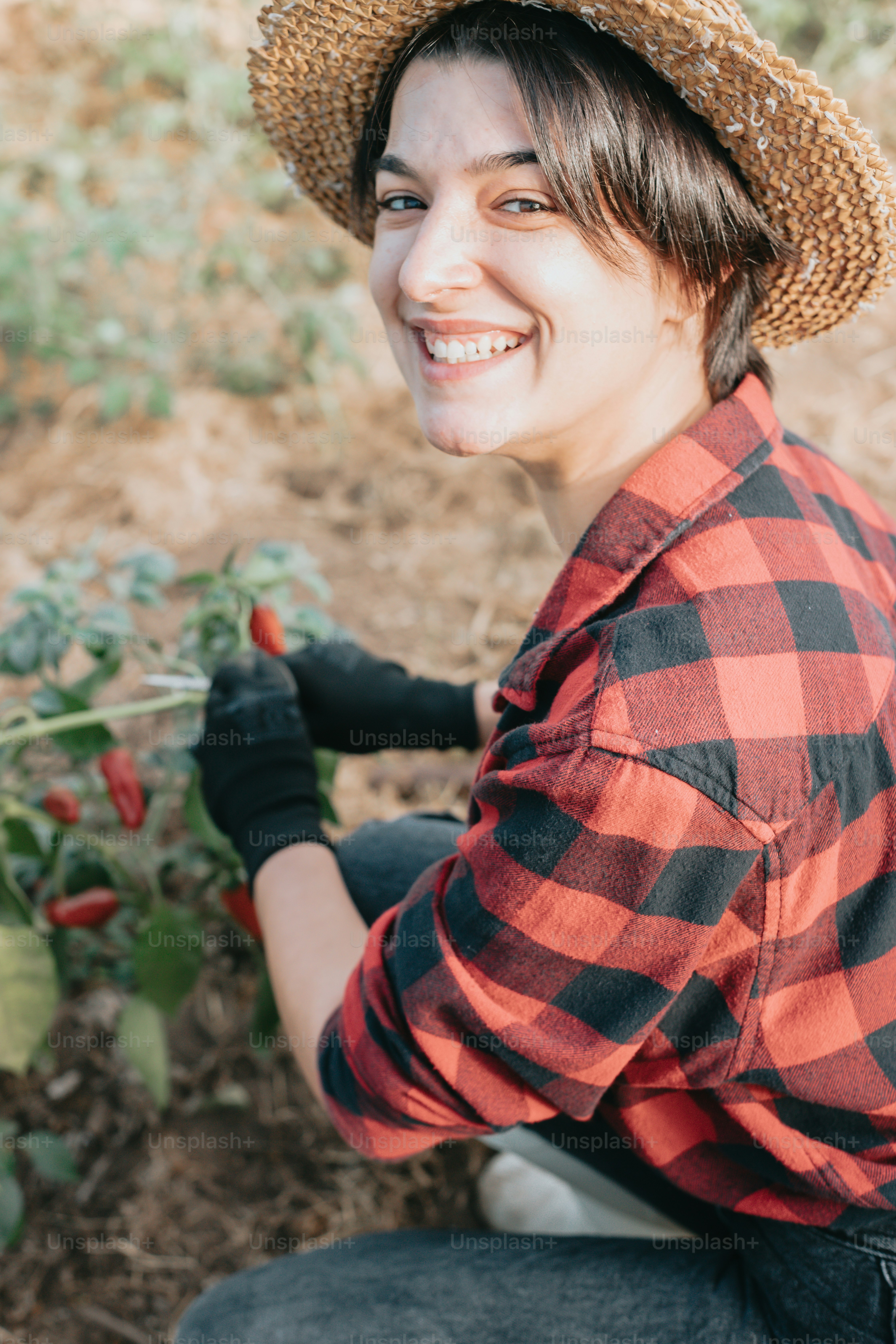 a woman wearing a straw hat and holding a plant