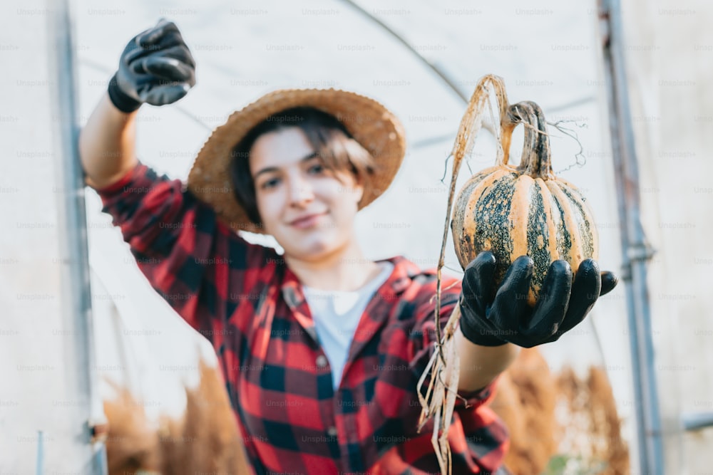 a woman in a hat holding a pumpkin
