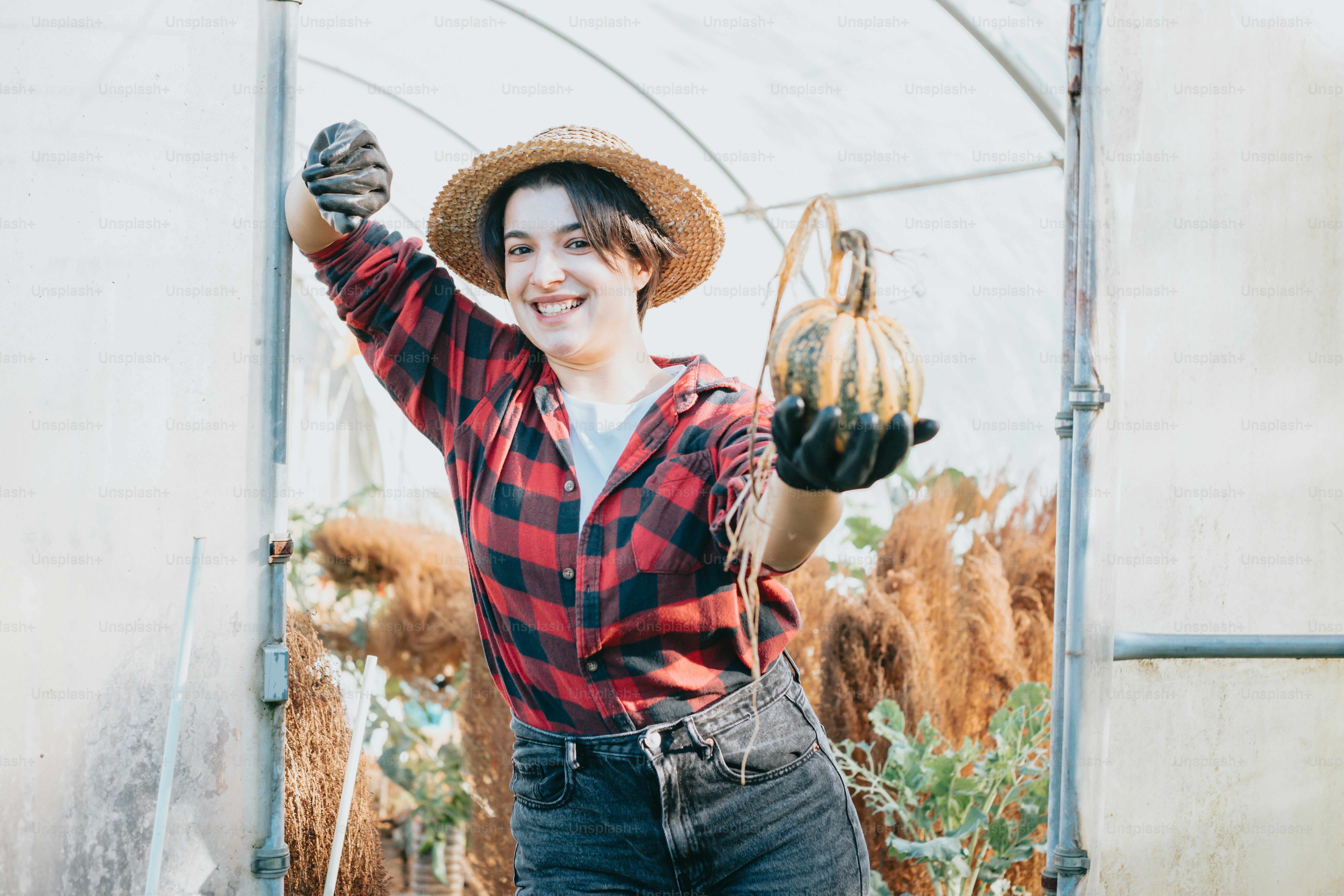 a woman wearing a hat and holding a pumpkin