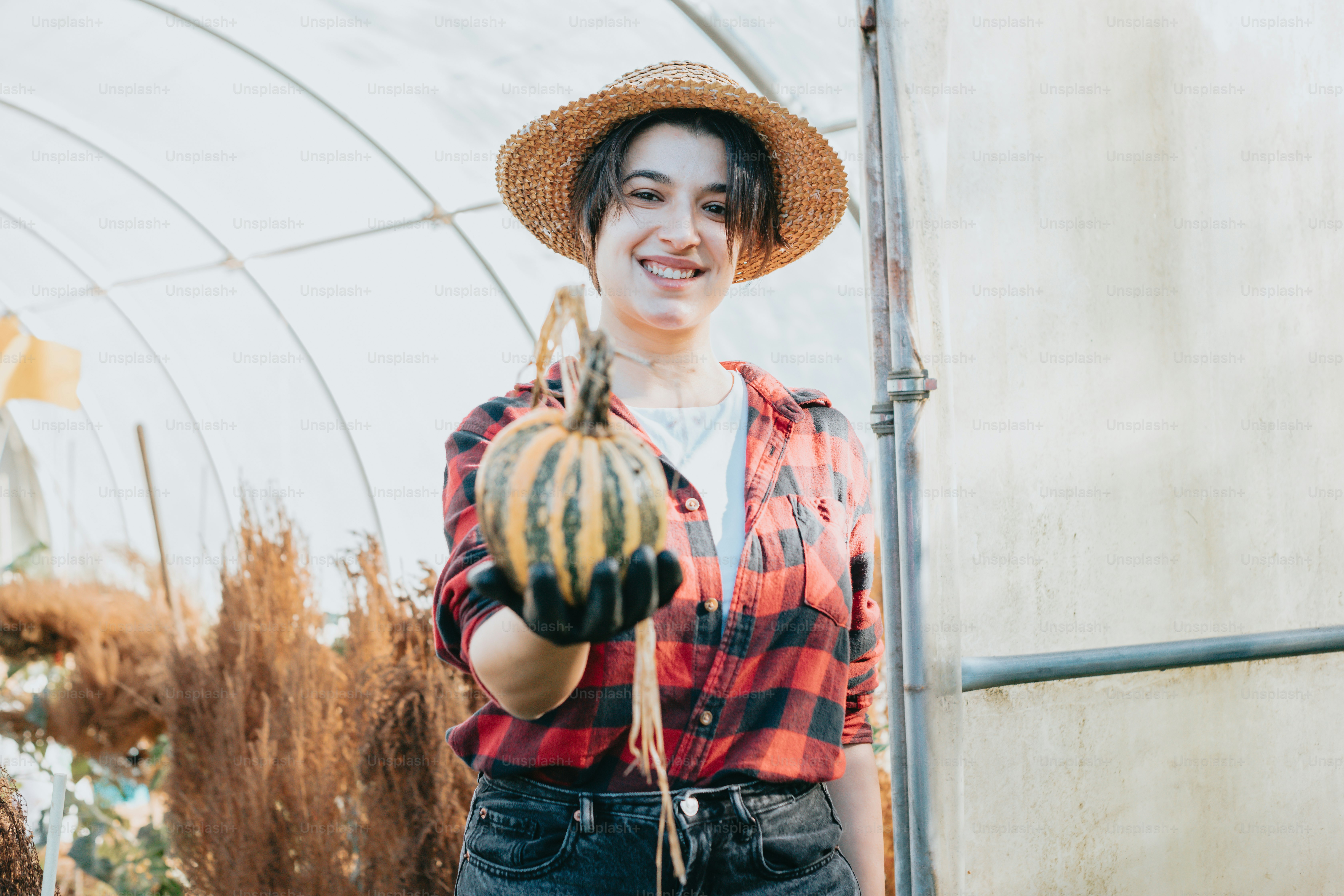 a woman wearing a straw hat holding a plant