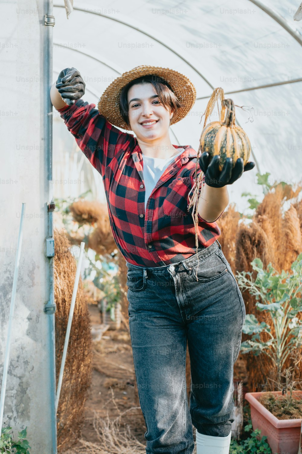 a woman wearing a hat and holding a plant in her hands