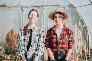 two women standing next to each other in a greenhouse