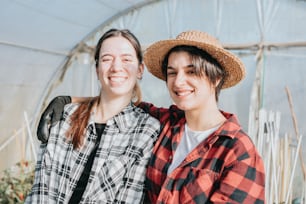 two women standing next to each other in a greenhouse