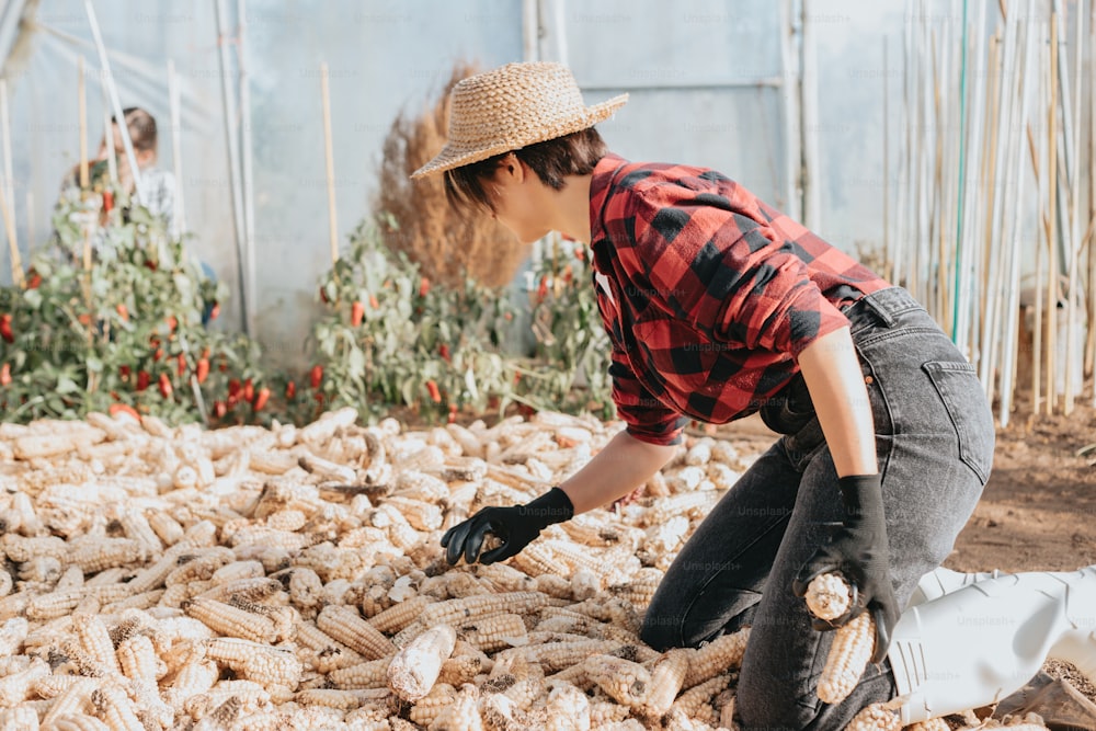 a woman kneeling down in front of a pile of corn