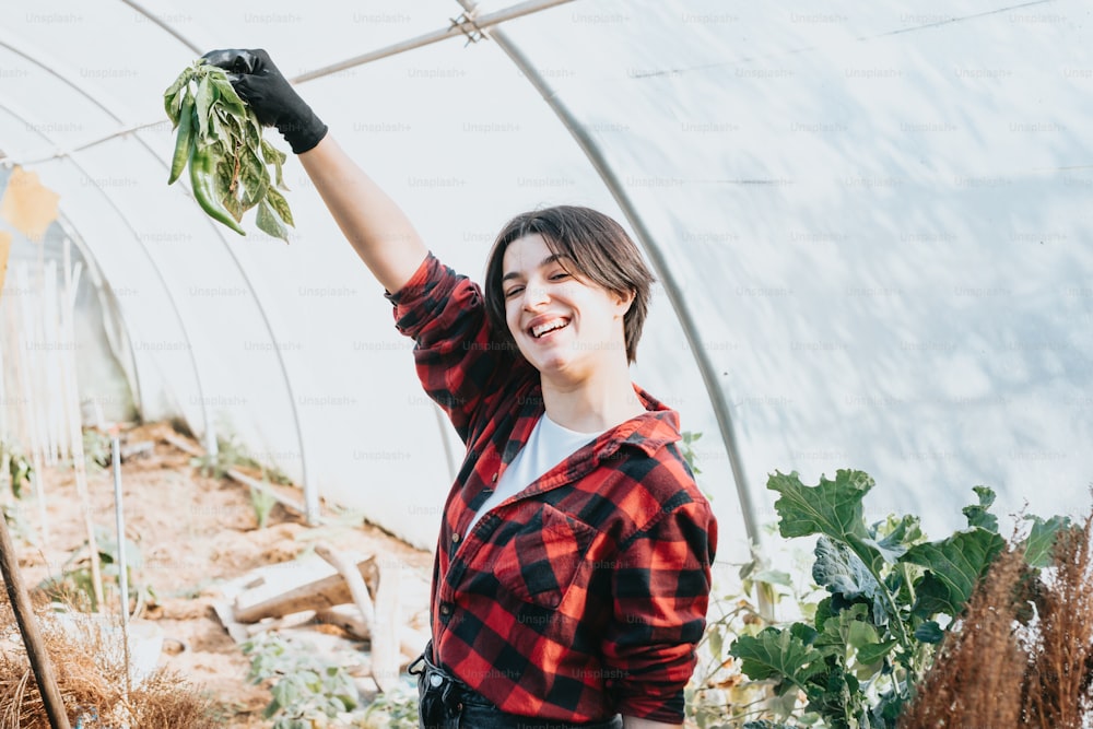 a woman holding up a plant in a greenhouse