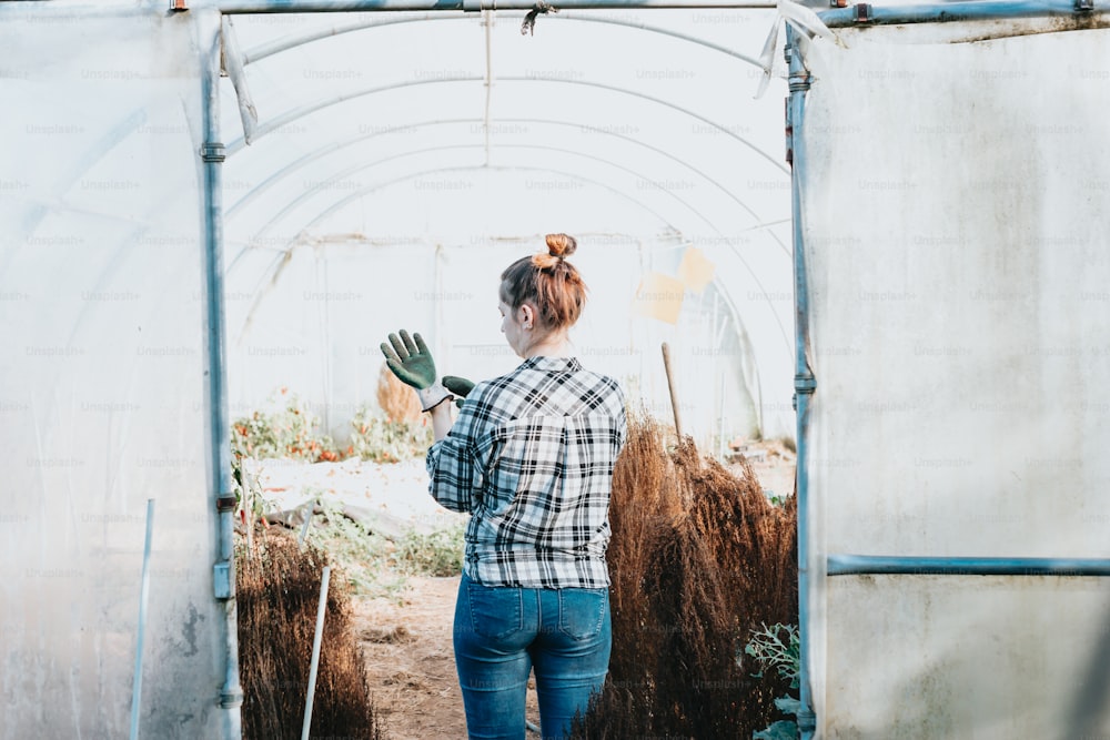 Una mujer parada en un invernadero sosteniendo una planta en maceta