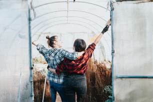 a couple of women standing next to each other in a greenhouse
