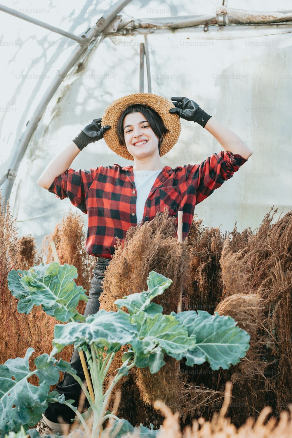 a woman wearing a straw hat in a greenhouse