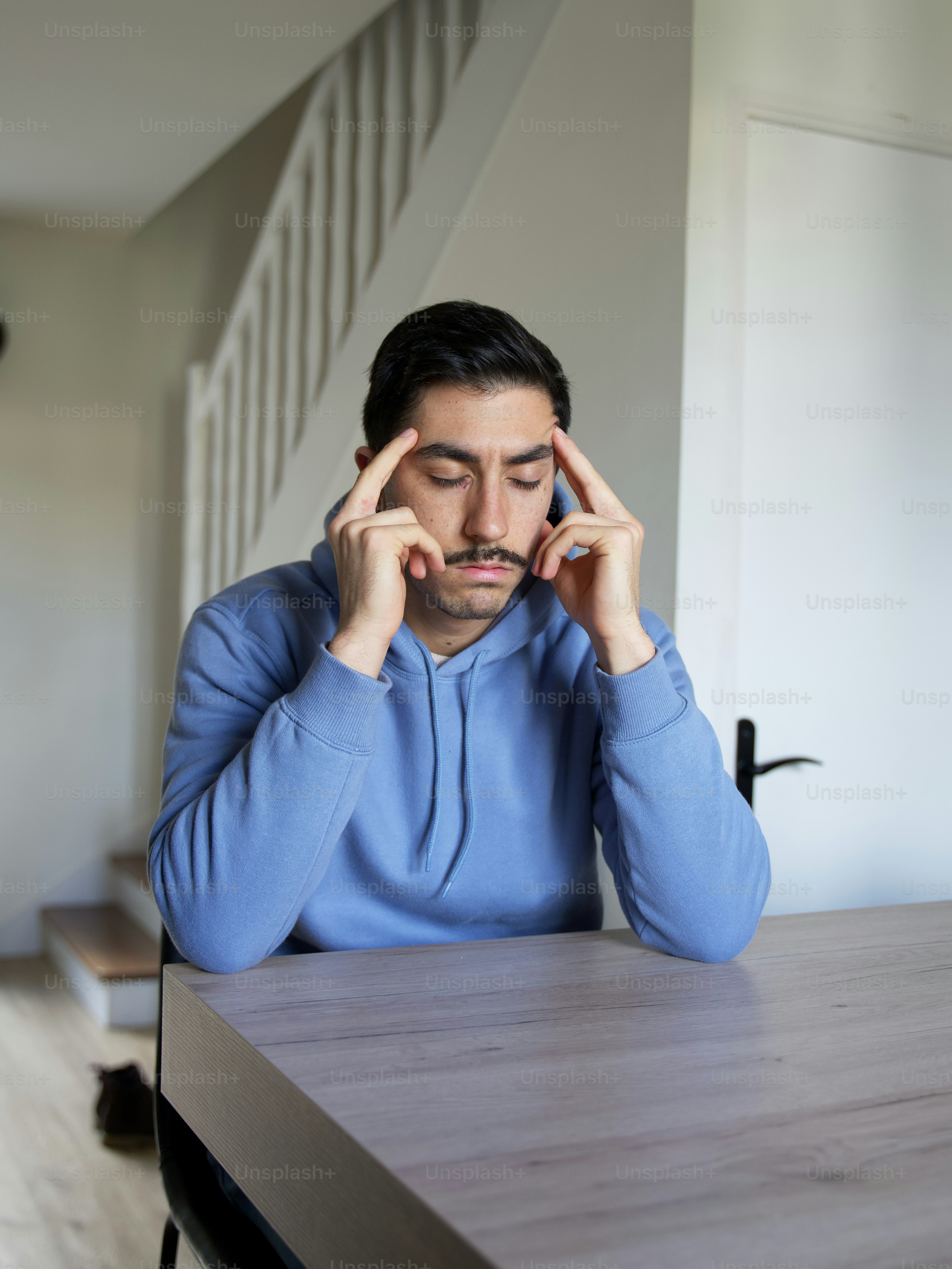 a person sitting at a desk with the hands on the face