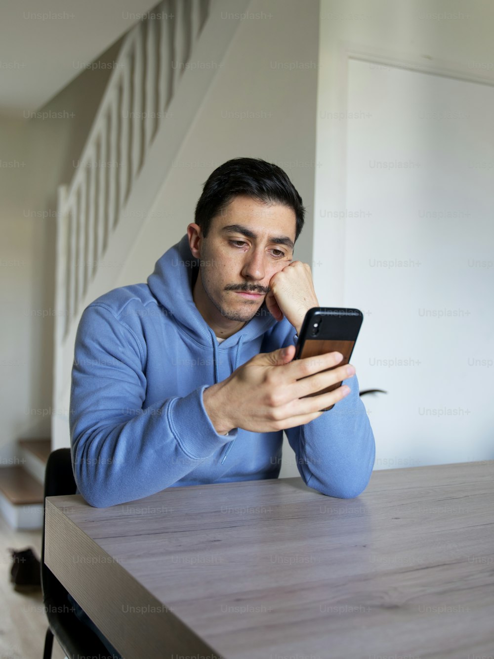 a man sitting at a table looking at a cell phone