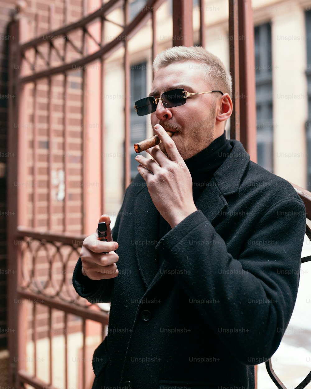 검은 코트를 입은 남자가 담배를 피우고 있다
