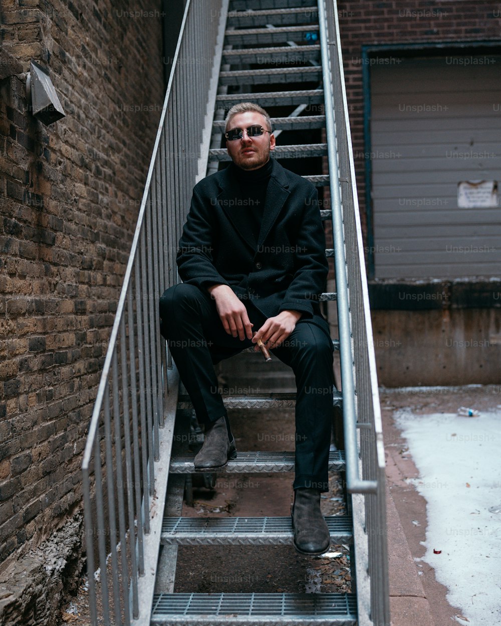 a man in a black suit sitting on a set of stairs