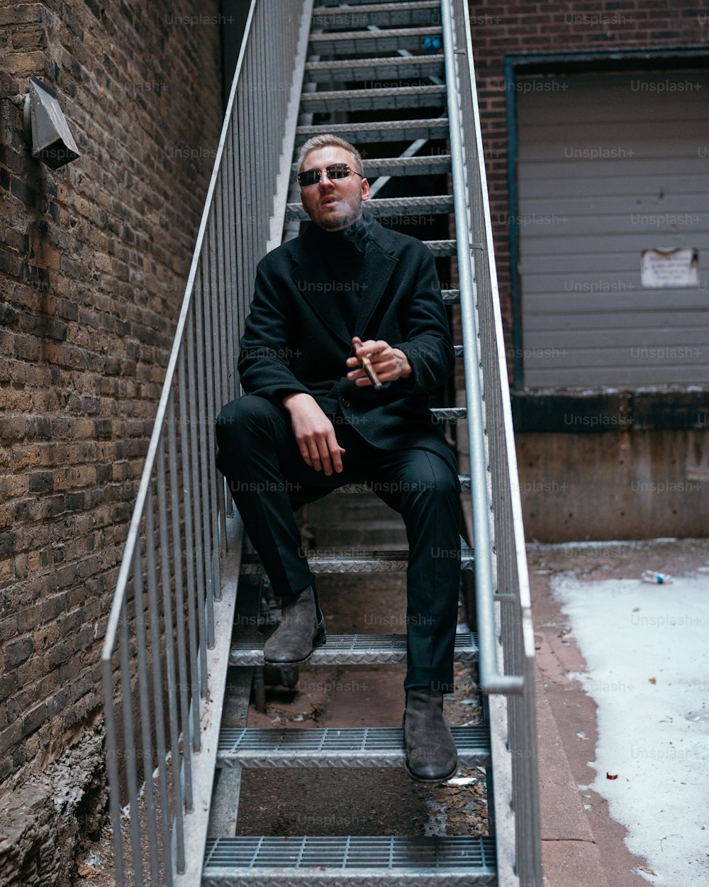 a man sitting on a set of stairs smoking a cigarette