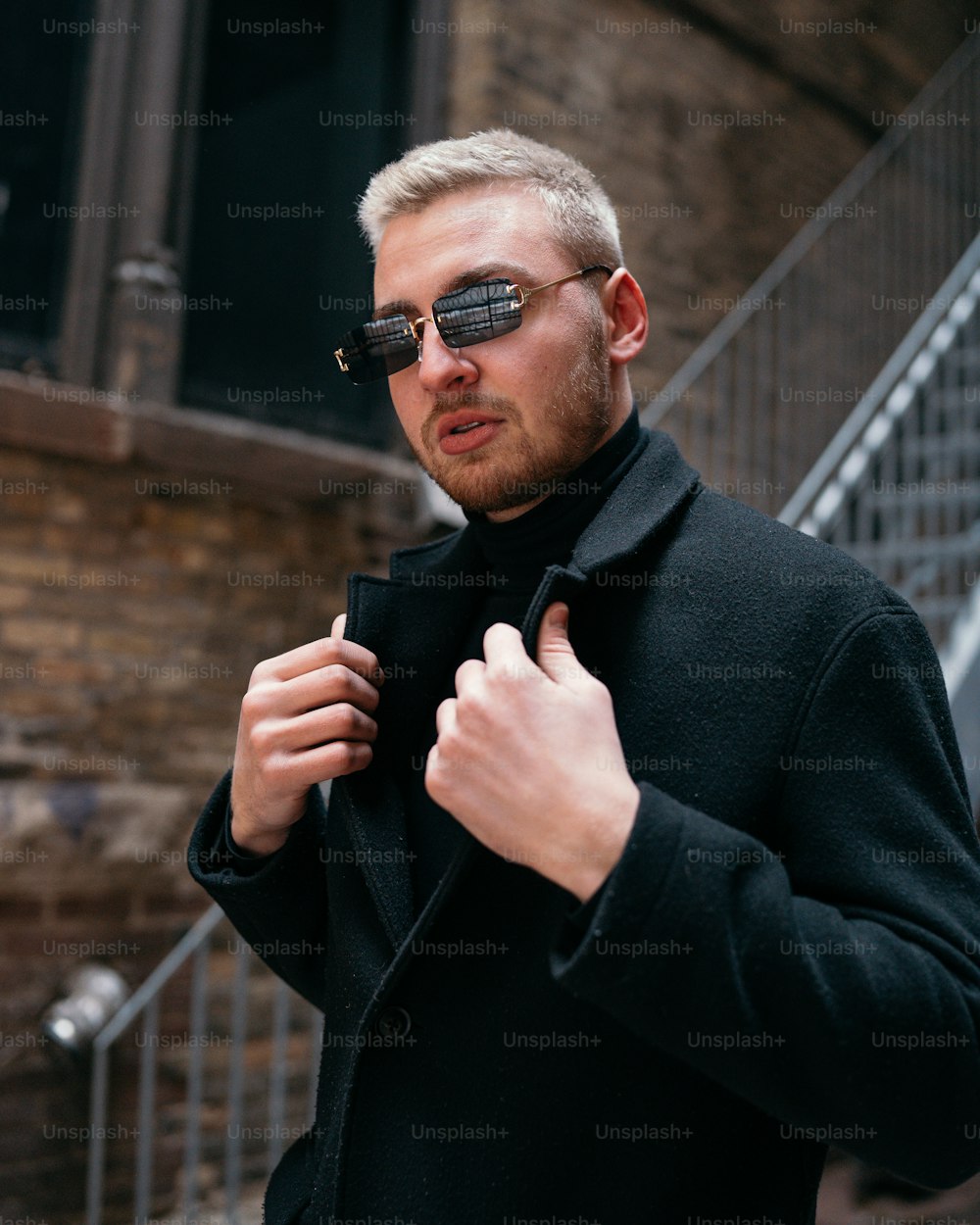 um homem de casaco preto e óculos escuros