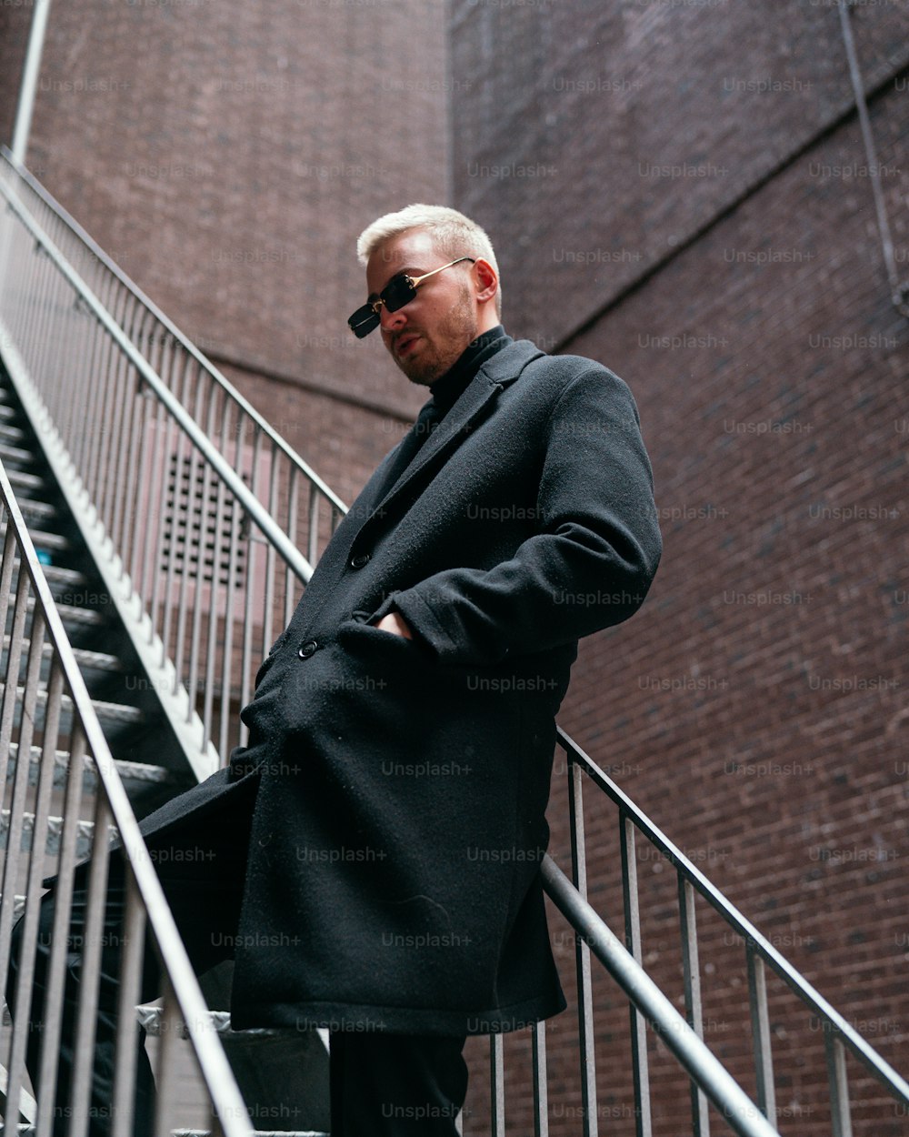 a man in a black coat is standing on a stair case