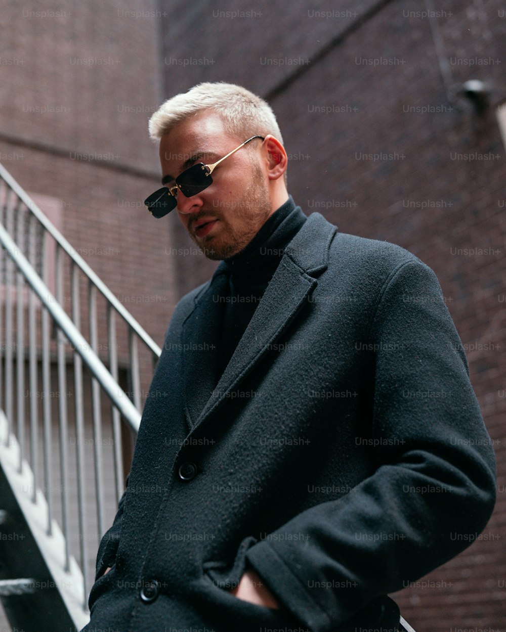 Un uomo in un cappotto nero e occhiali da sole