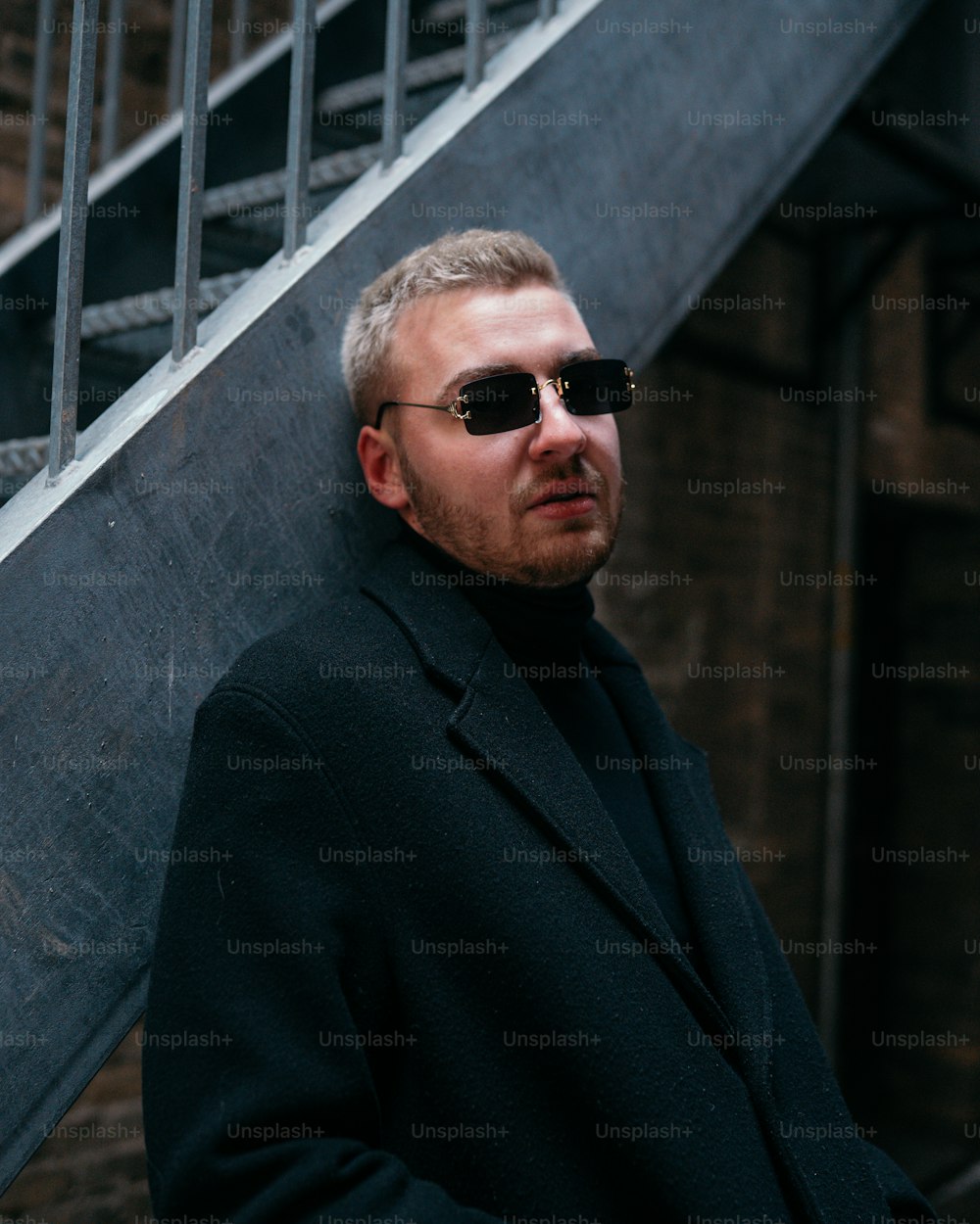 a man wearing sunglasses standing next to a stair case