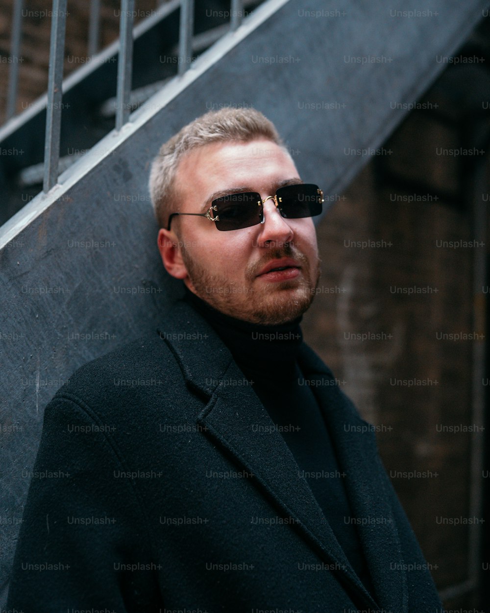 a man wearing sunglasses standing in front of a stair case