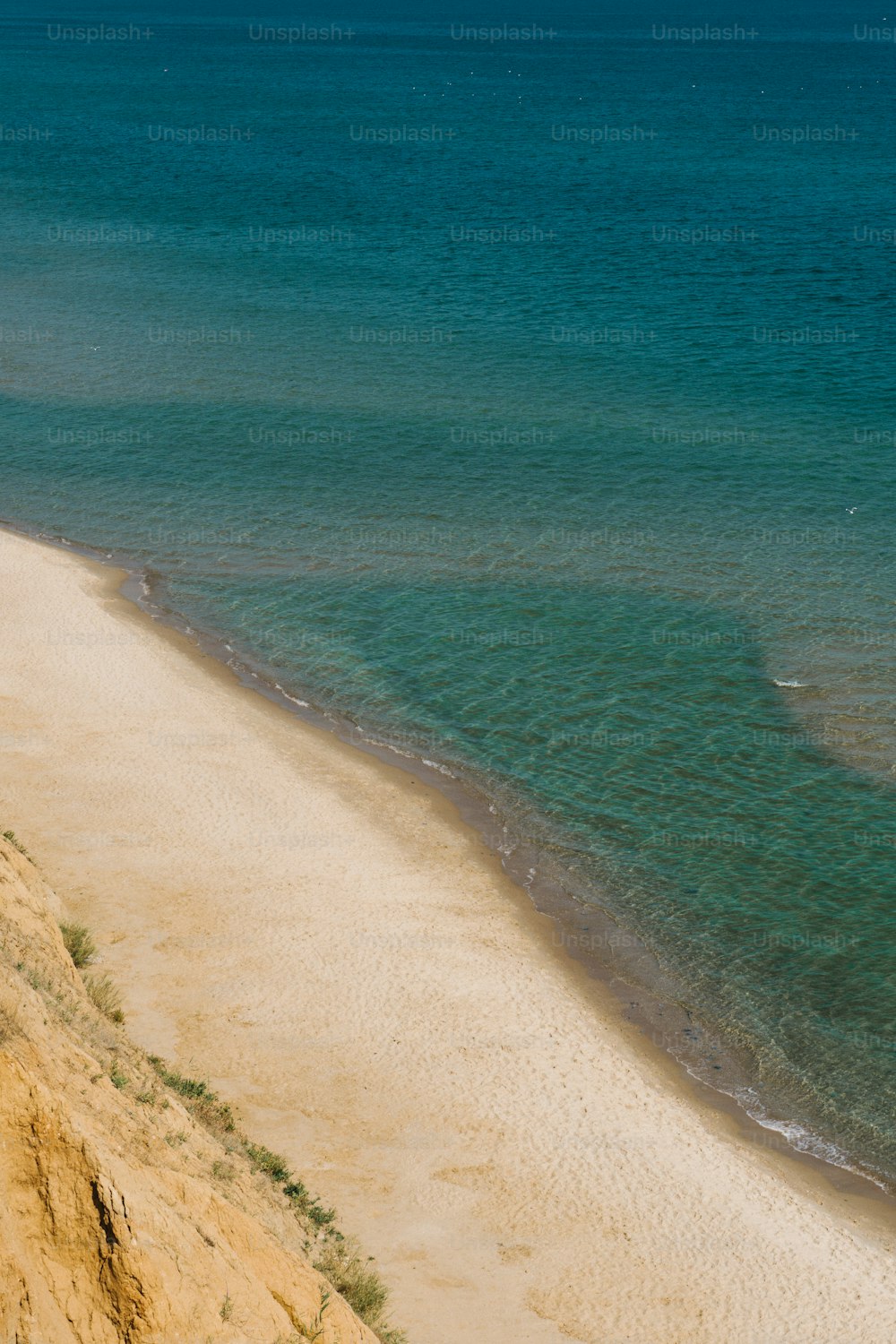 a couple of people riding horses on top of a sandy beach