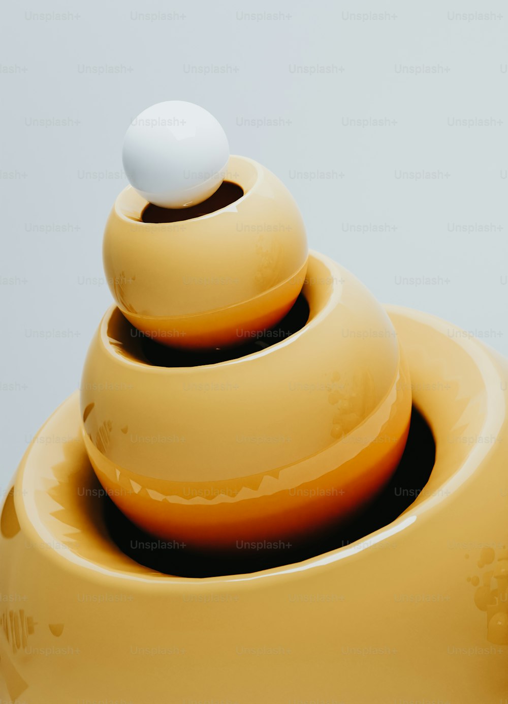 a yellow vase with a white ball on top of it