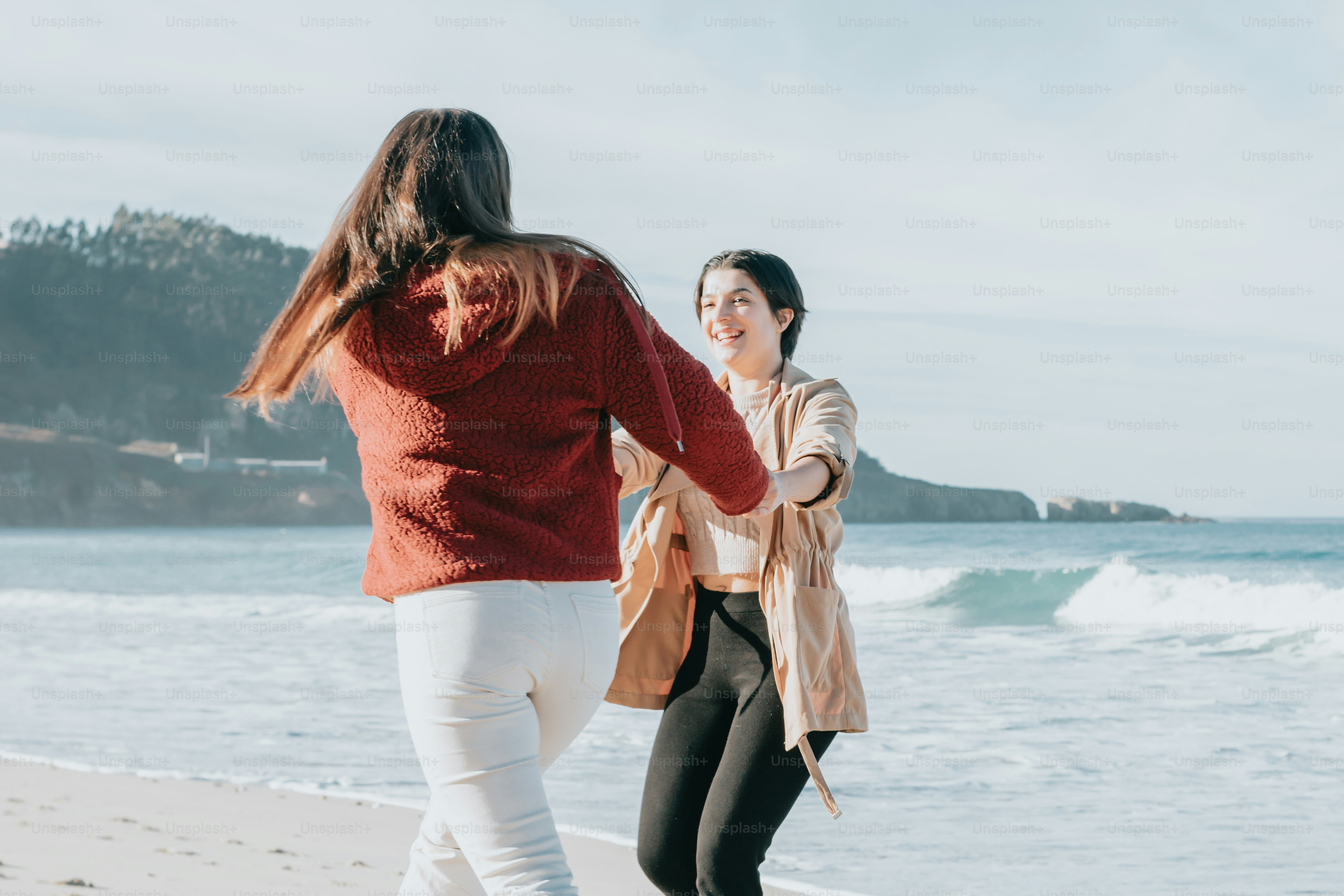two women walking along the beach holding hands