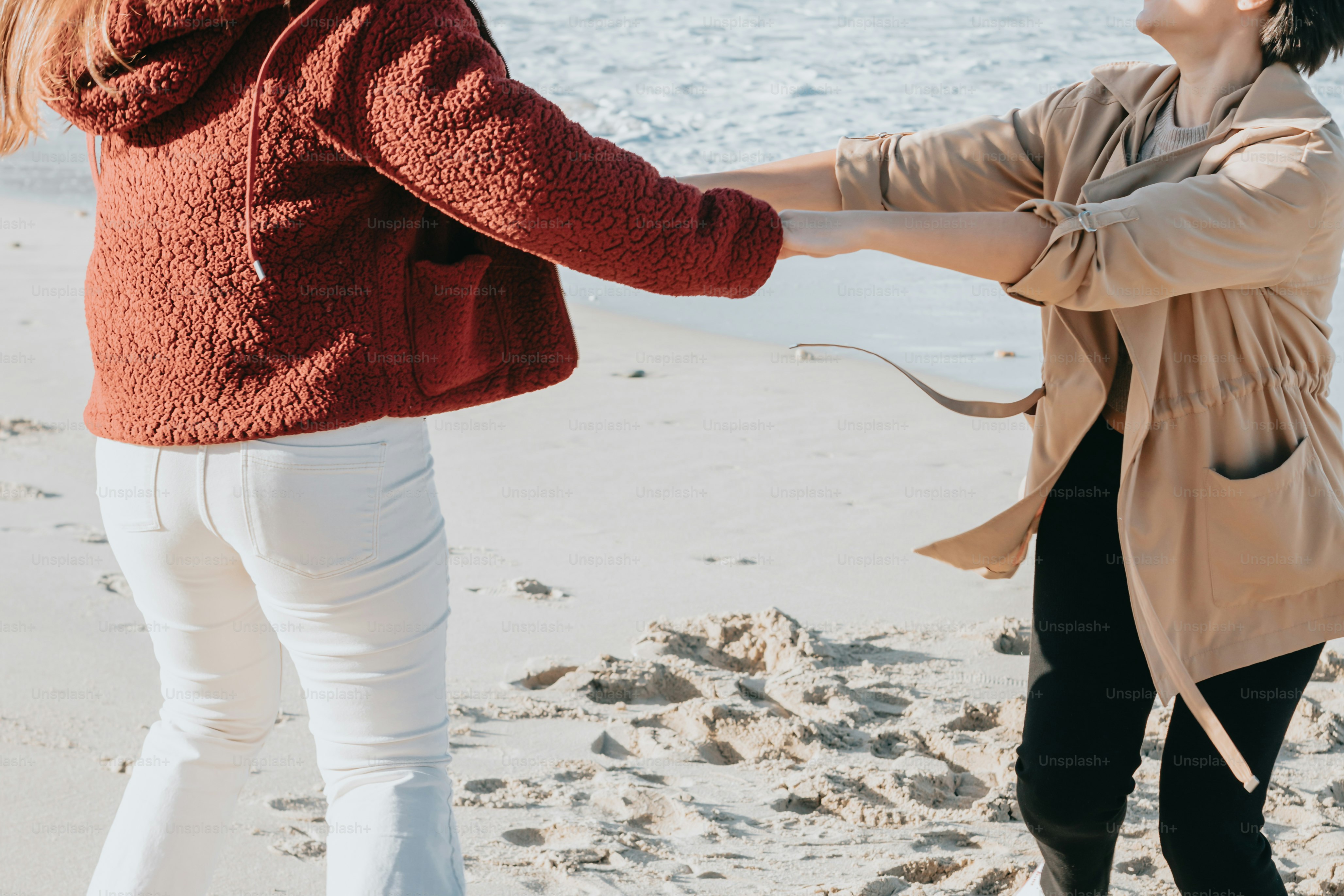 a couple of women standing on top of a sandy beach
