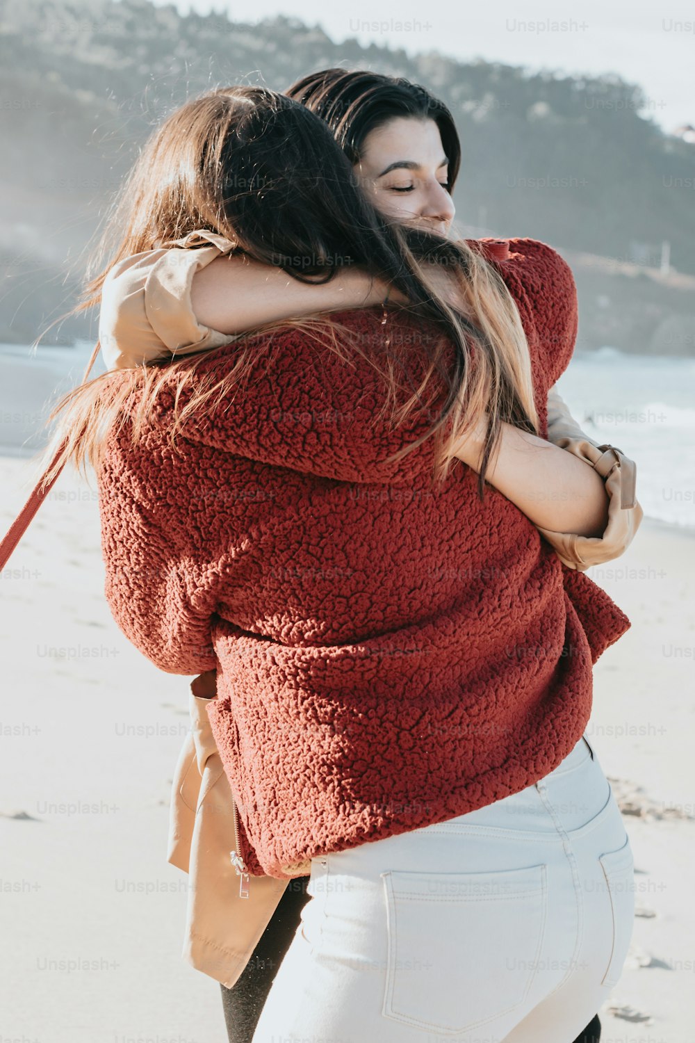 Una mujer abraza a otra mujer en la playa