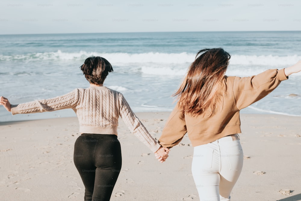 手をつないで浜辺を歩く2人の女性