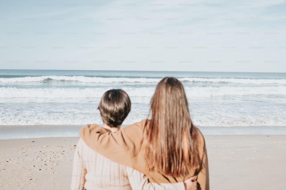 um par de pessoas que estão de pé na areia