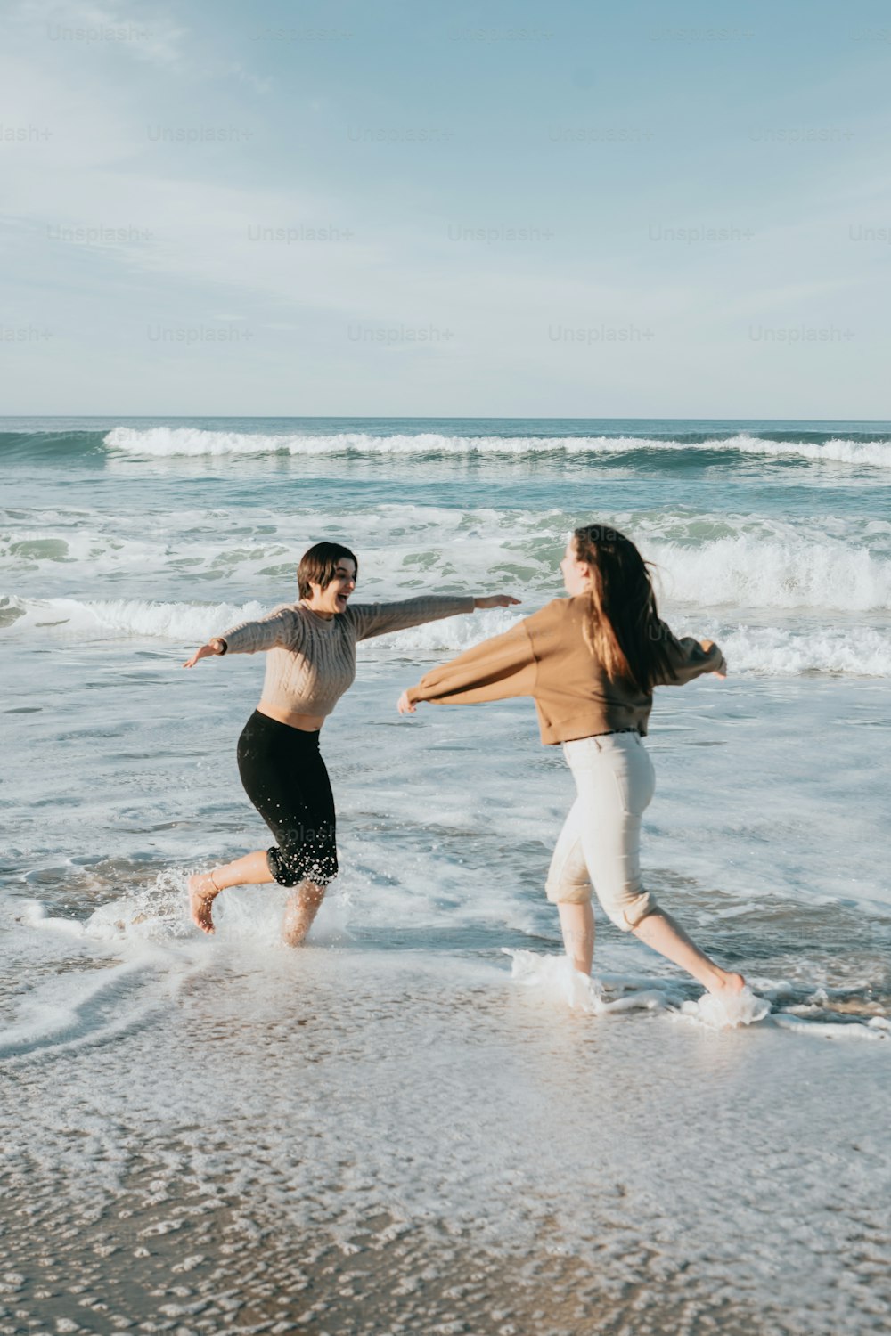 Due donne che corrono nell'acqua in spiaggia
