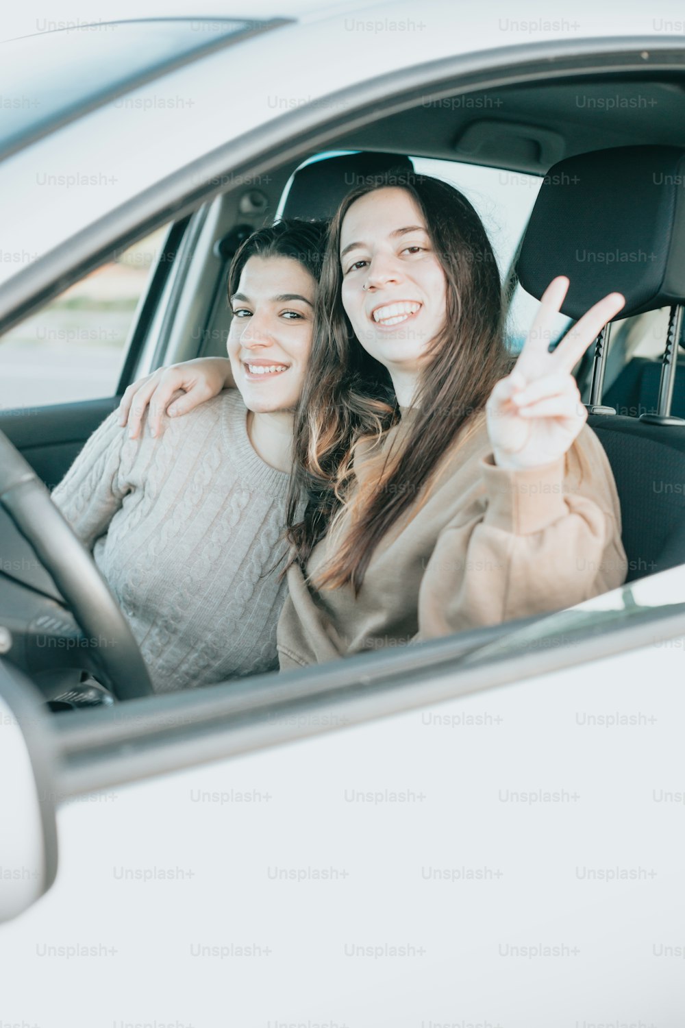 two women sitting in a car giving the peace sign