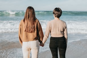 손을 잡고 해변을 걷는 두 여자