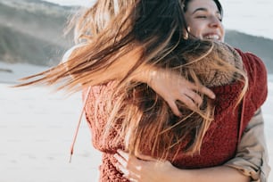 a woman hugging another woman on the beach