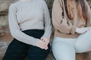 two women sitting next to each other on a rock