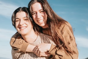 two women are smiling and hugging each other