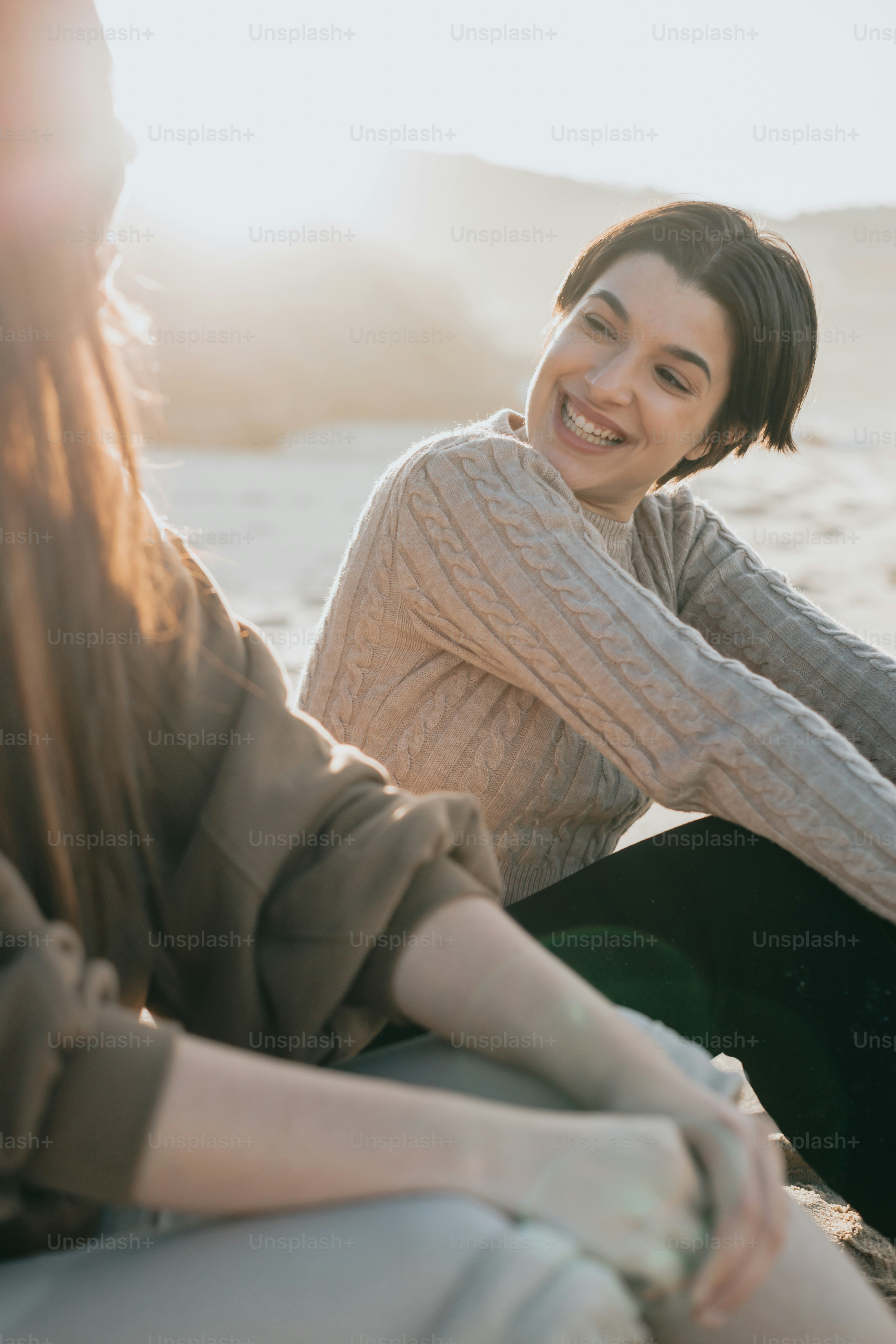 a couple of women sitting next to each other on a beach
