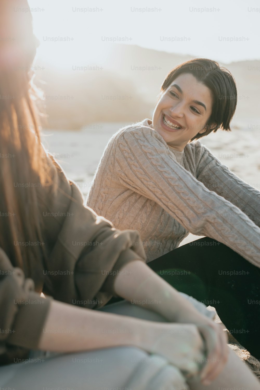 해변에 나란히 앉아 있는 두 명의 여성