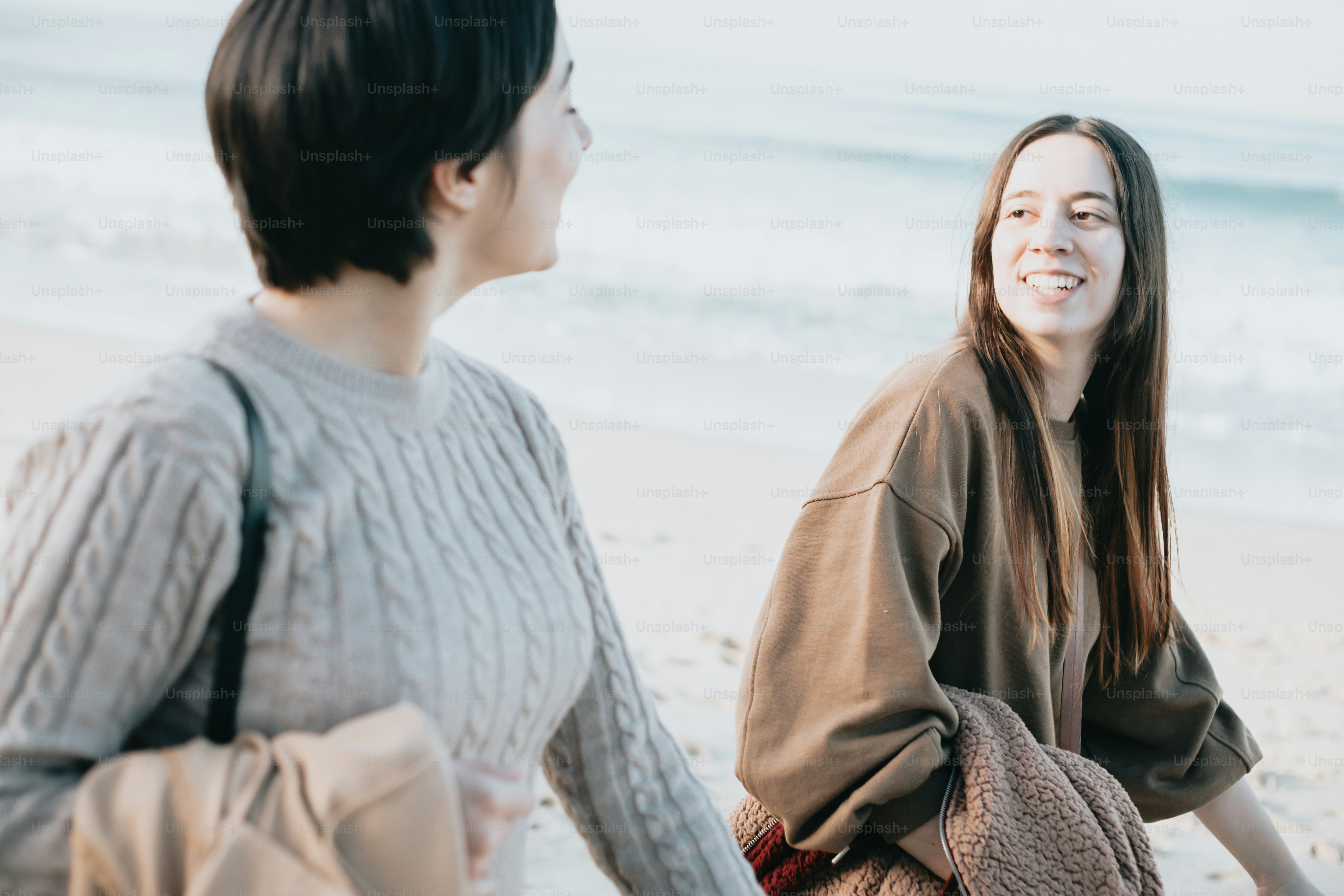 a couple of women standing next to each other on a beach