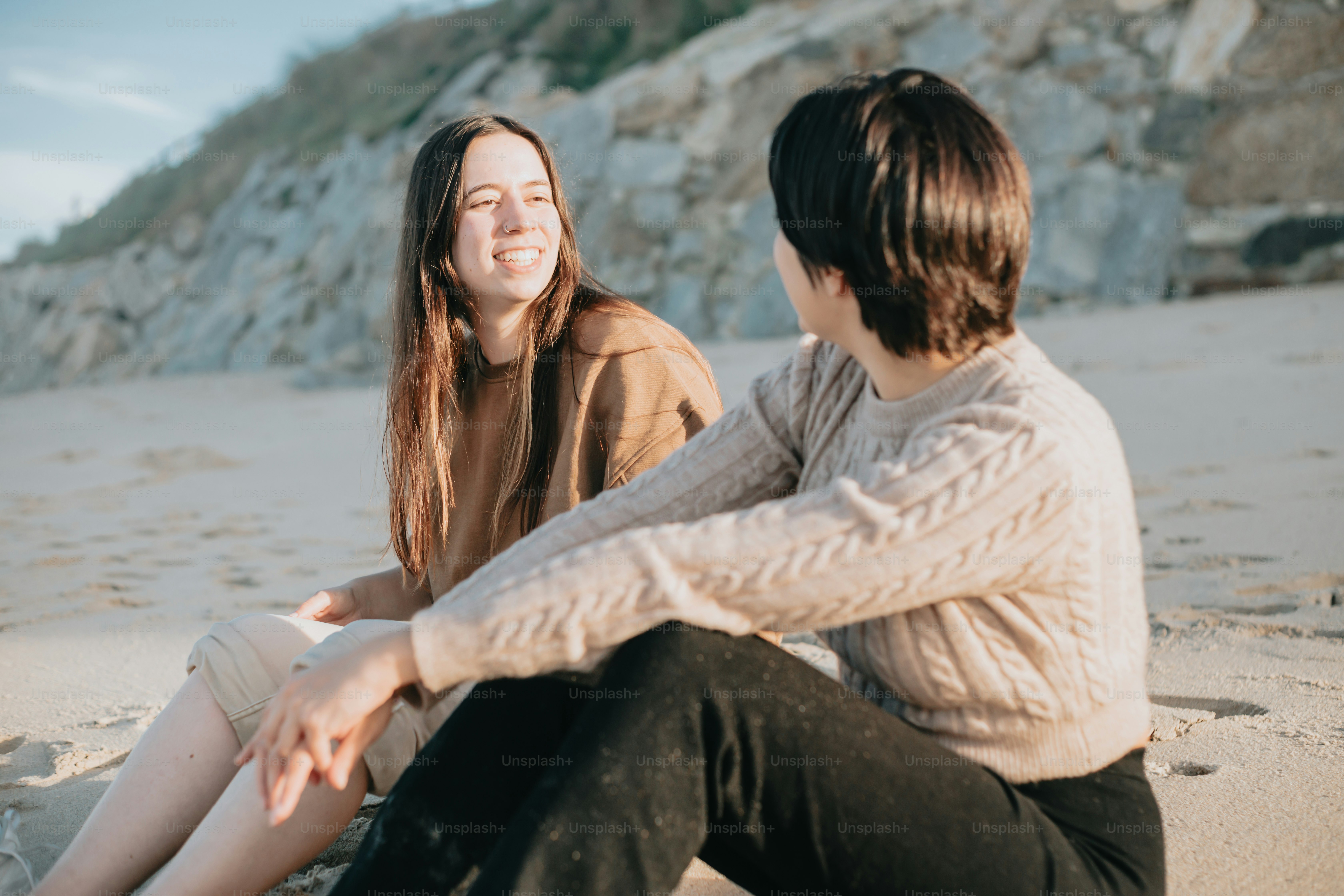 a couple of women sitting on top of a sandy beach