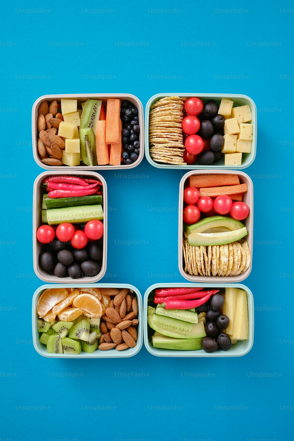 um conjunto de quatro recipientes plásticos cheios de diferentes tipos de alimentos