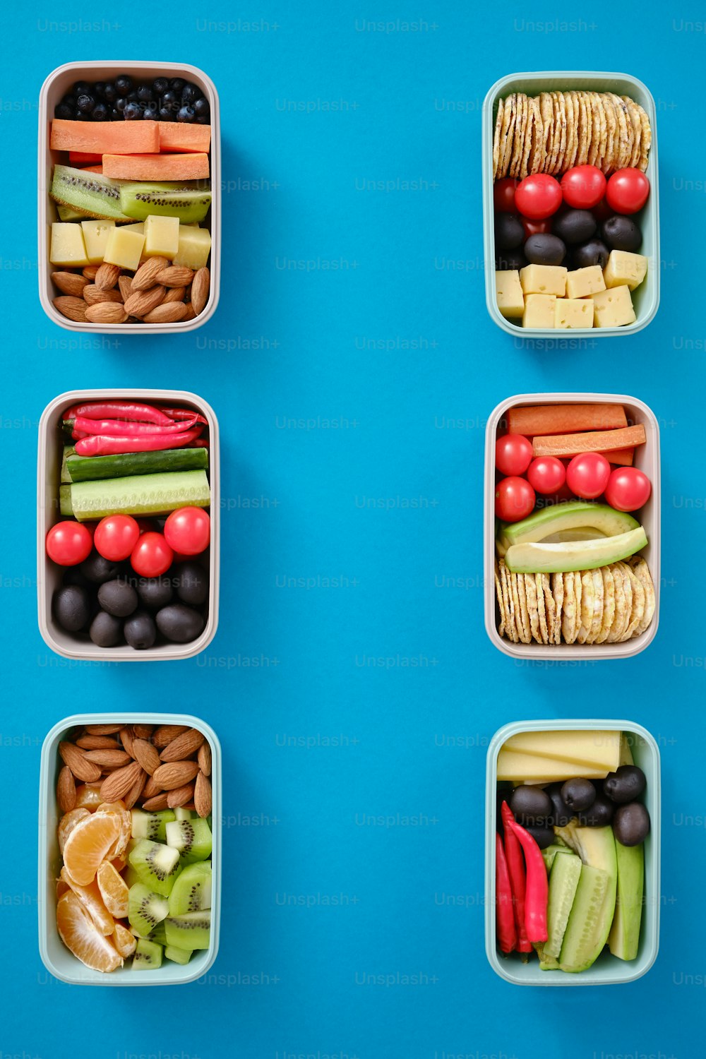 quatro recipientes plásticos cheios de diferentes tipos de alimentos