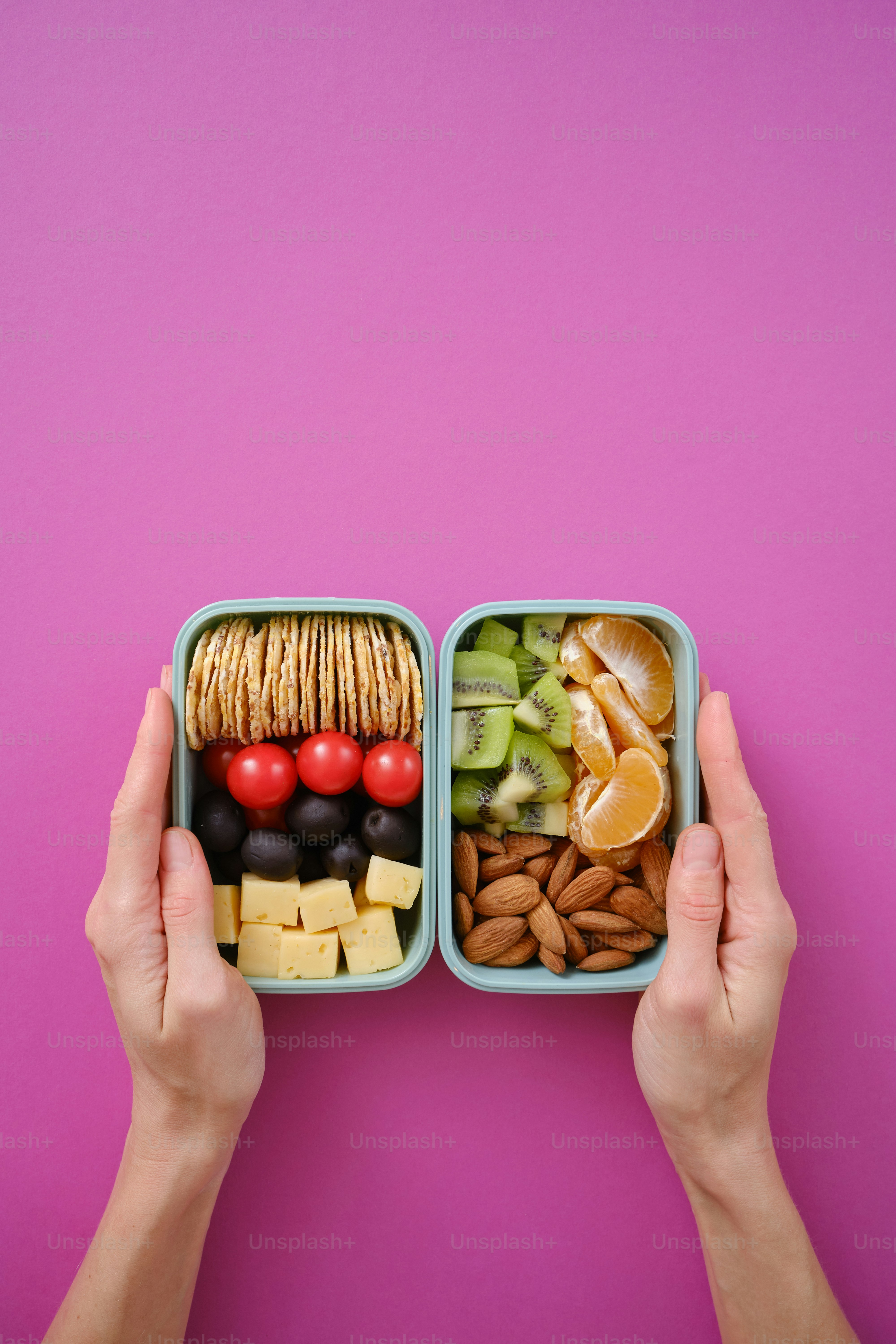 Lunchboxes with healthy snacks on a colored background