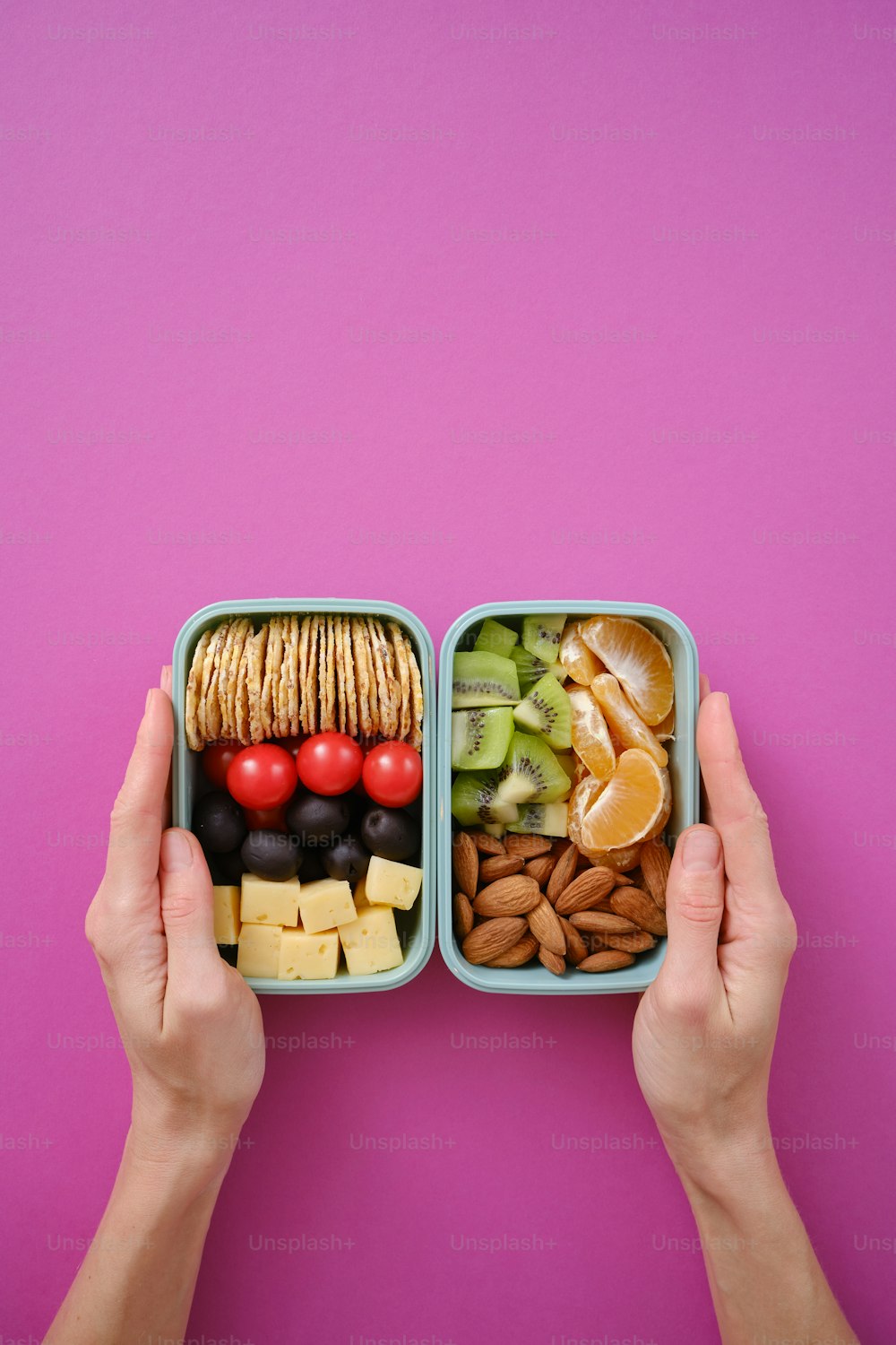 a person holding a container of food on a pink background