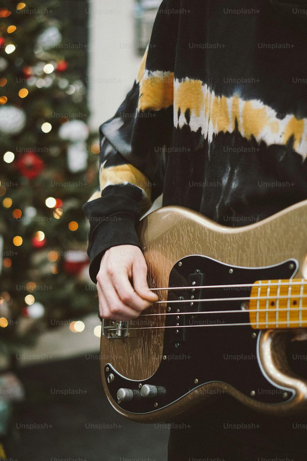 a person holding a bass guitar in front of a christmas tree
