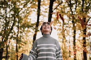 Ein Junge in einem gestreiften Pullover wirft Blätter in die Luft